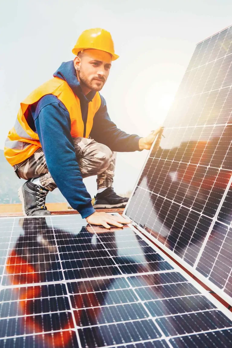 Ein Arbeiter, der auf einem Dach eine Photovoltaik-Anlage installiert.